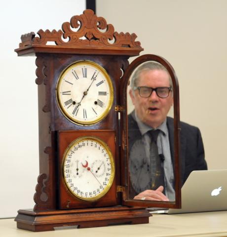 Man looking through the window of antique clock.